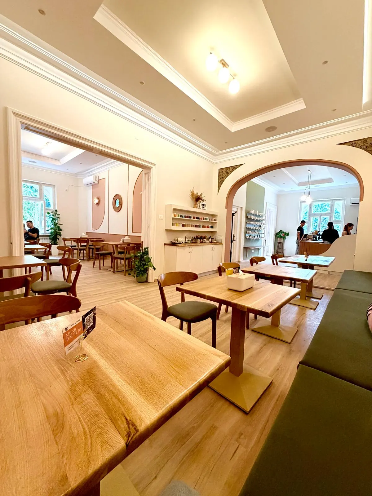 Interiorul Caferamica — mese din lemn, arcada spre bar și raftul cu vopsele